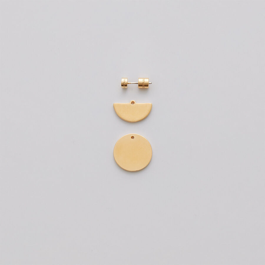 Pair of earrings with half-circle and circle pendants on a plain background.