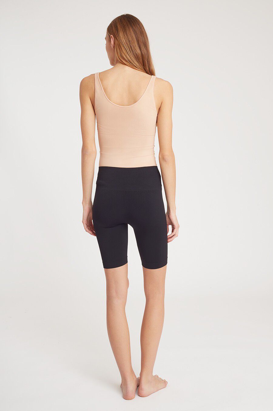 Seamless Long Shorts Person seen from behind, wearing a sleeveless top and knee-length shorts, standing barefoot.