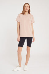 Woman standing, wearing a t-shirt and shorts with sneakers.