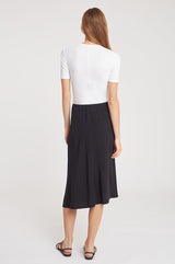 Woman facing away wearing a short-sleeve top and mid-length skirt.