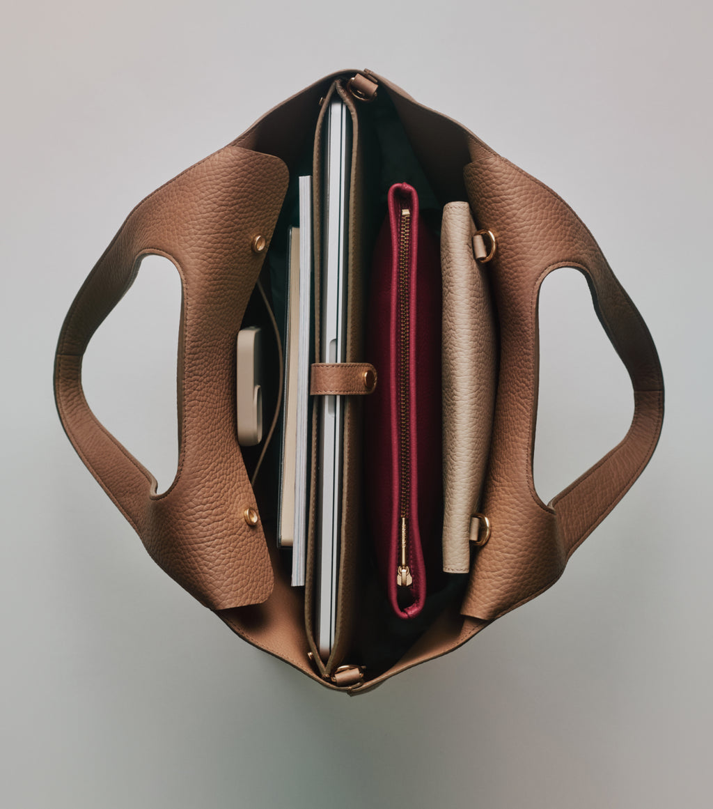 Open handbag showing organized contents inside like a laptop and folders.