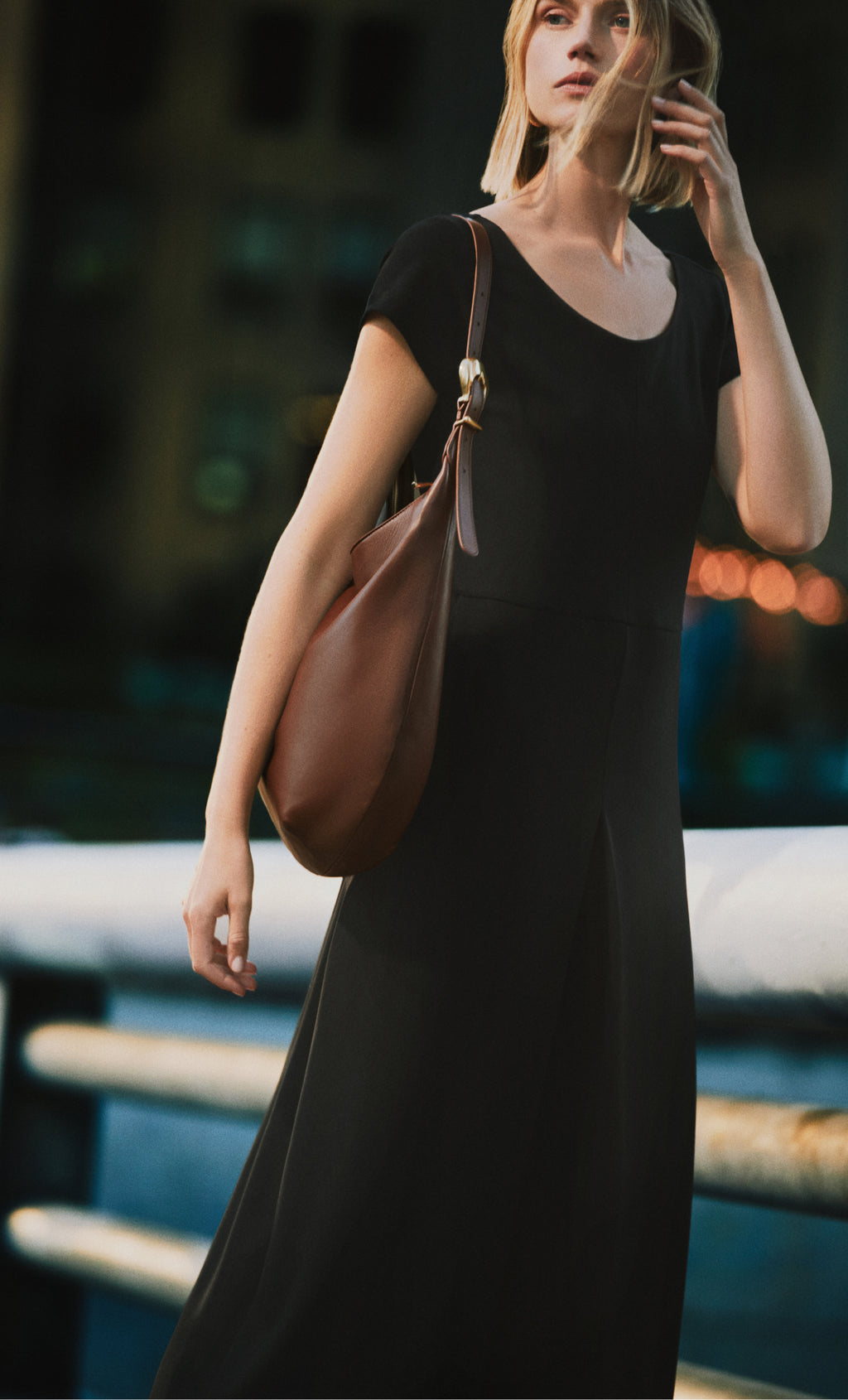 Person in a dress carrying a shoulder bag outdoors.