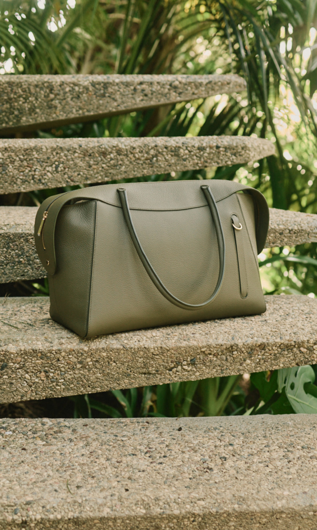 Travel bag on outdoor steps surrounded by greenery.