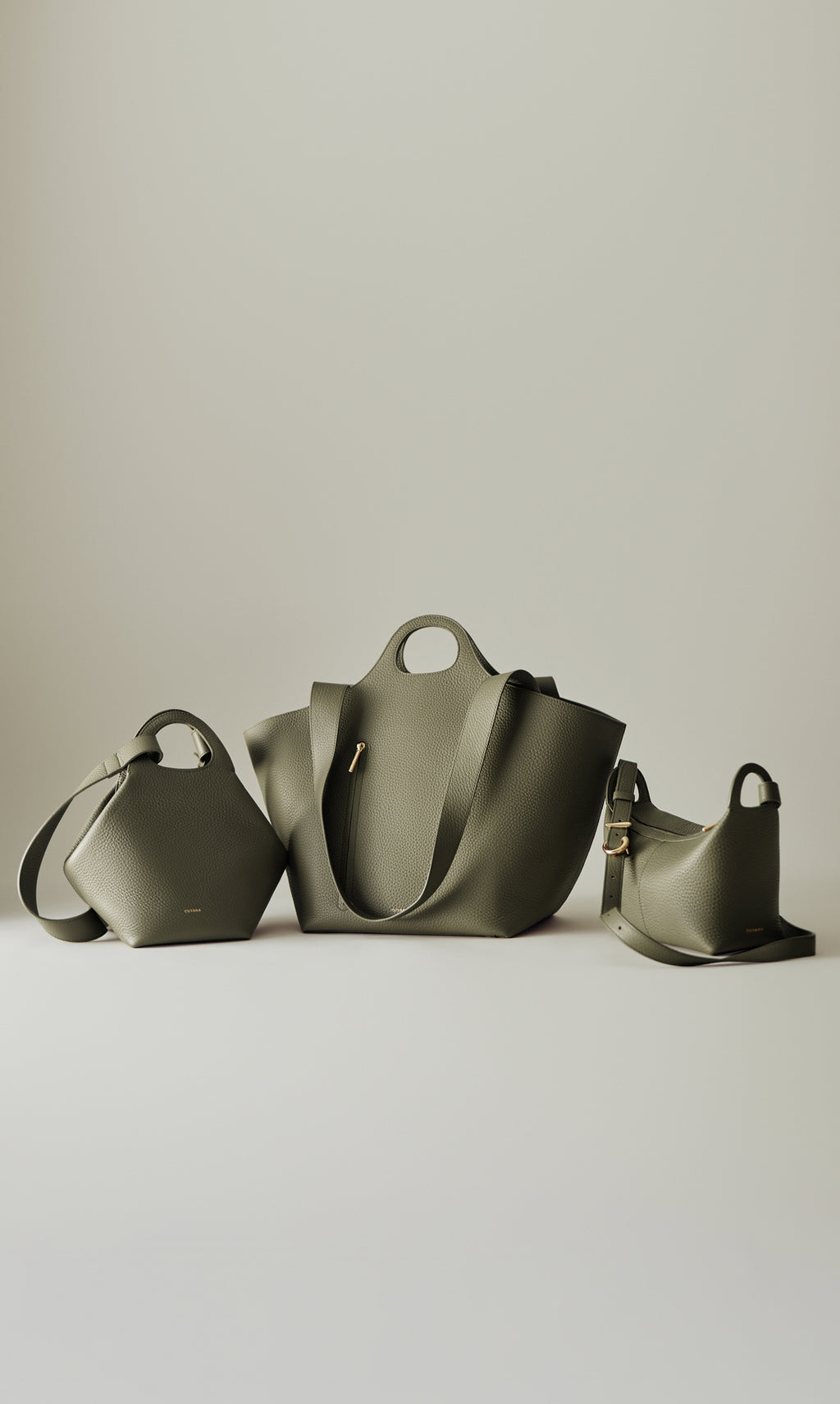 Three stylish handbags displayed on a flat surface.