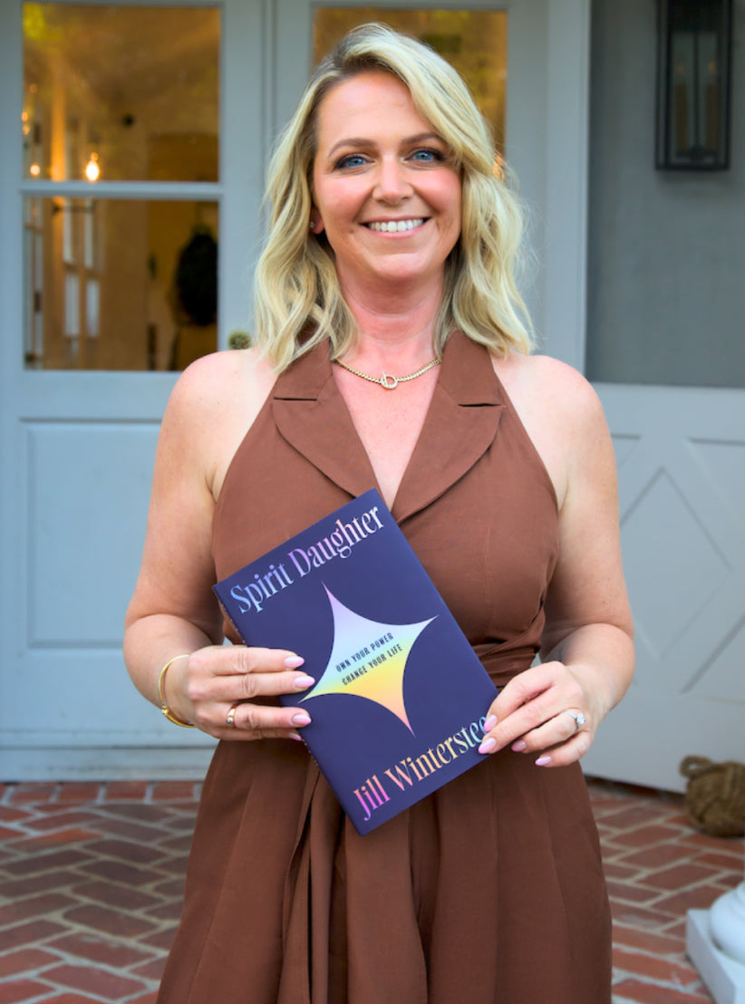 Person holding a book while standing on a brick surface in front of a door.