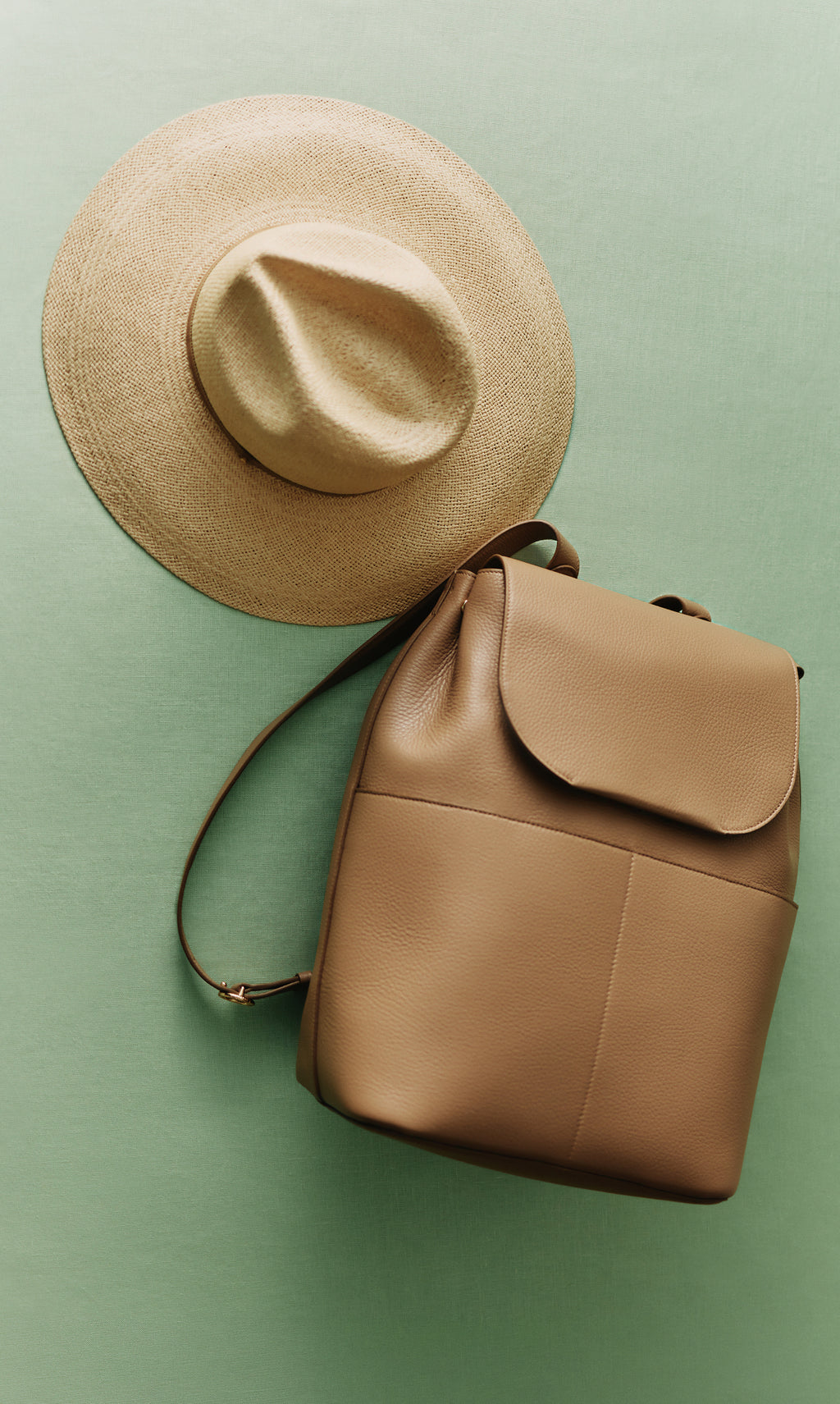 Hat lying next to a backpack on a flat surface.