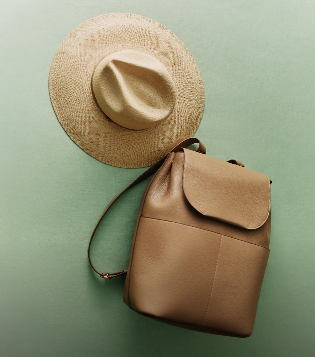 Wide-brim hat next to a backpack against a plain background.