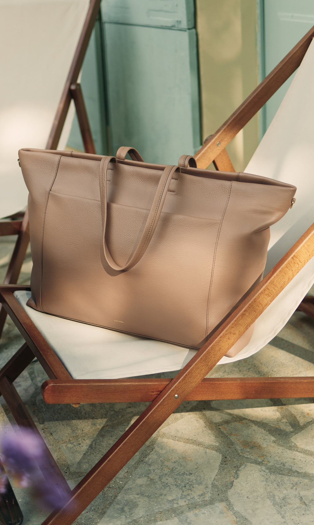 Travel bag on deck chair beside a wall in an outdoor setting.