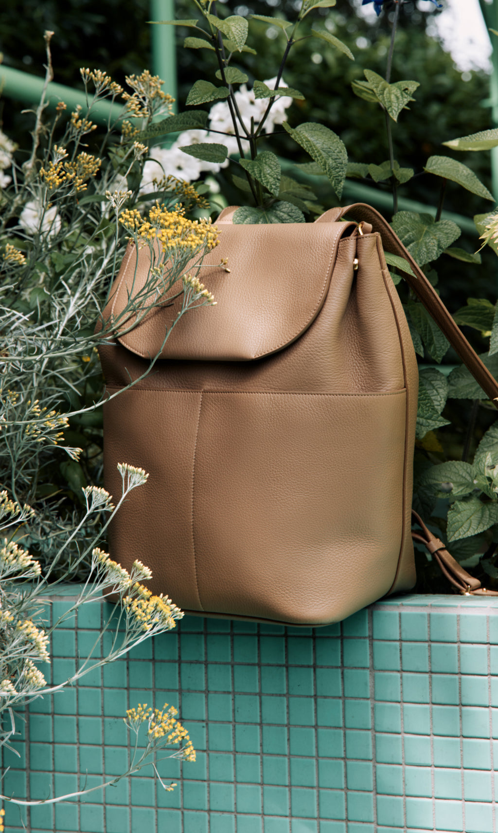 Backpack on tiled ledge surrounded by plants.