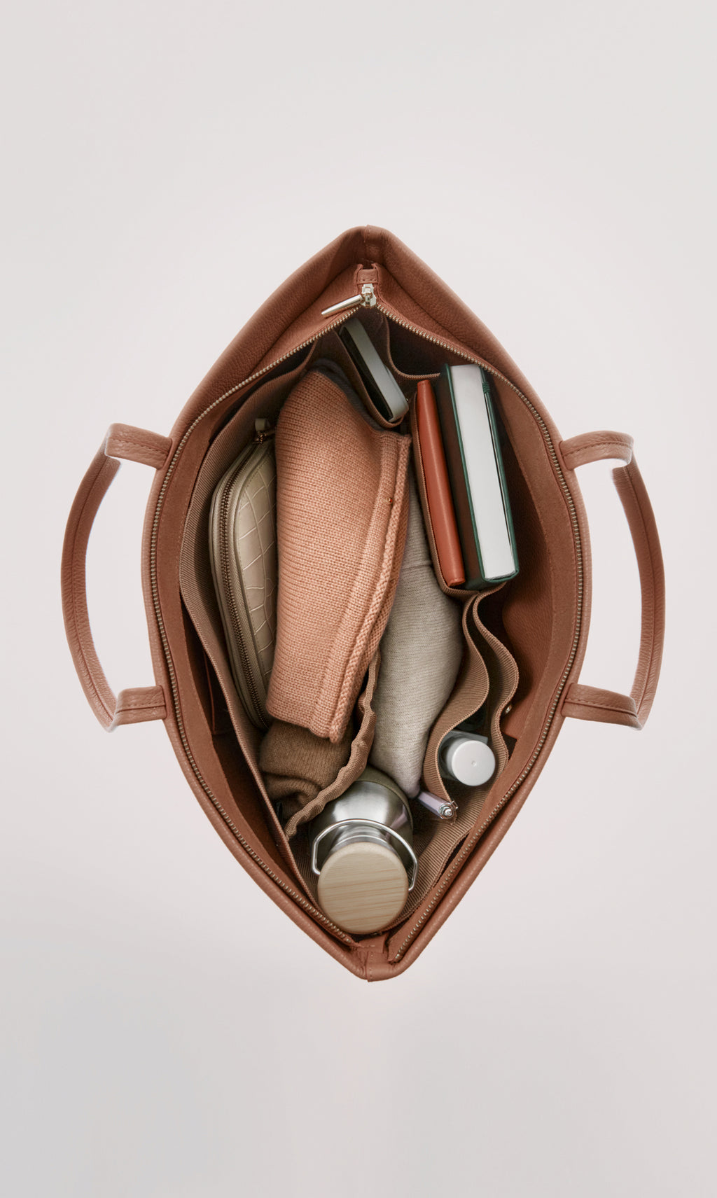 Open travel bag with books, pouches, bottle, and a small container inside.