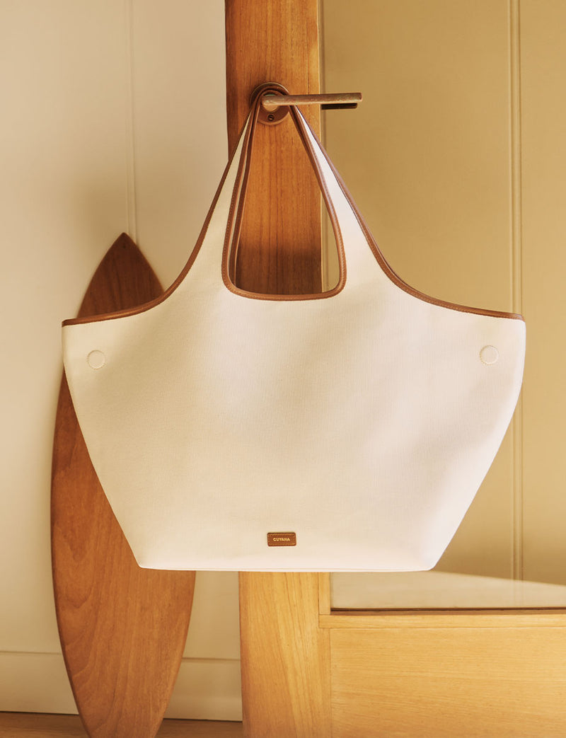 Large handbag hanging on a door handle indoors.