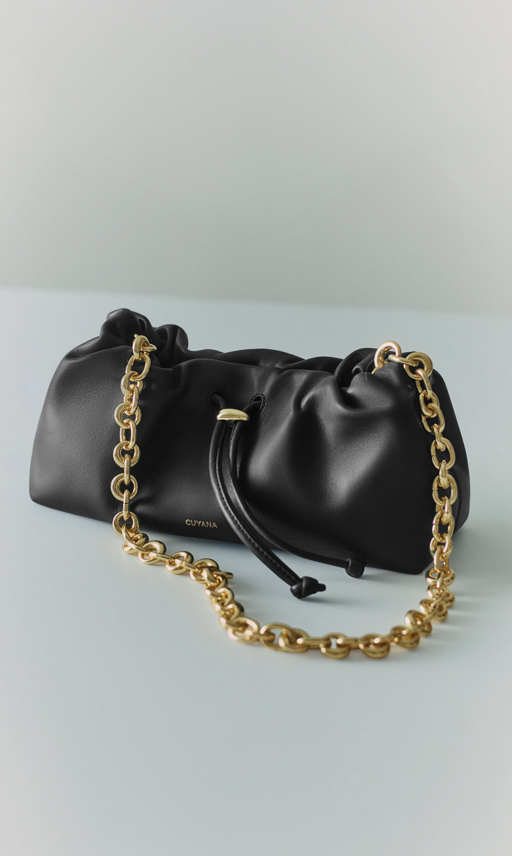 Leather clutch with a chunky chain strap and drawstring closure.