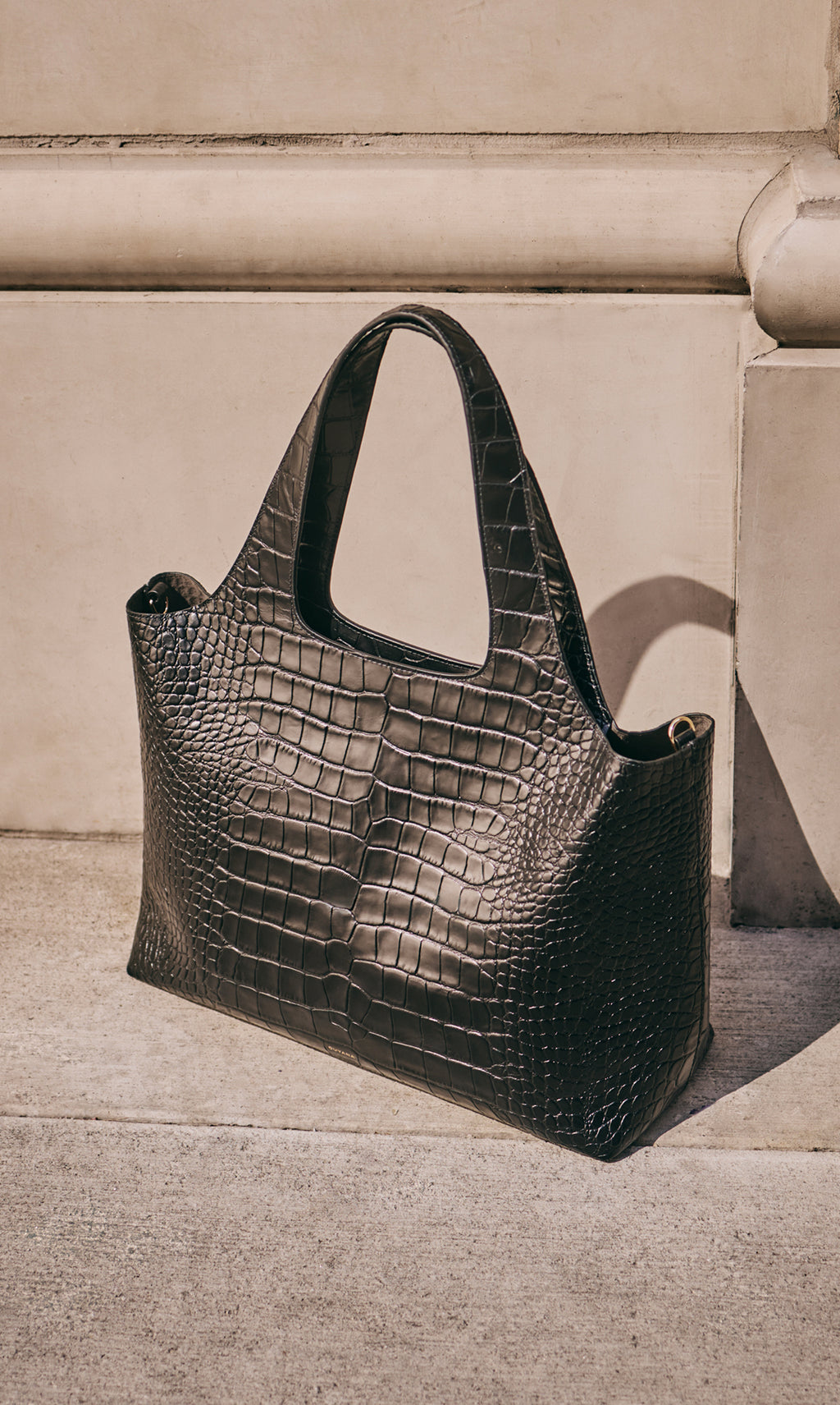 Tote bag with croc-embossed leather on sidewalk.