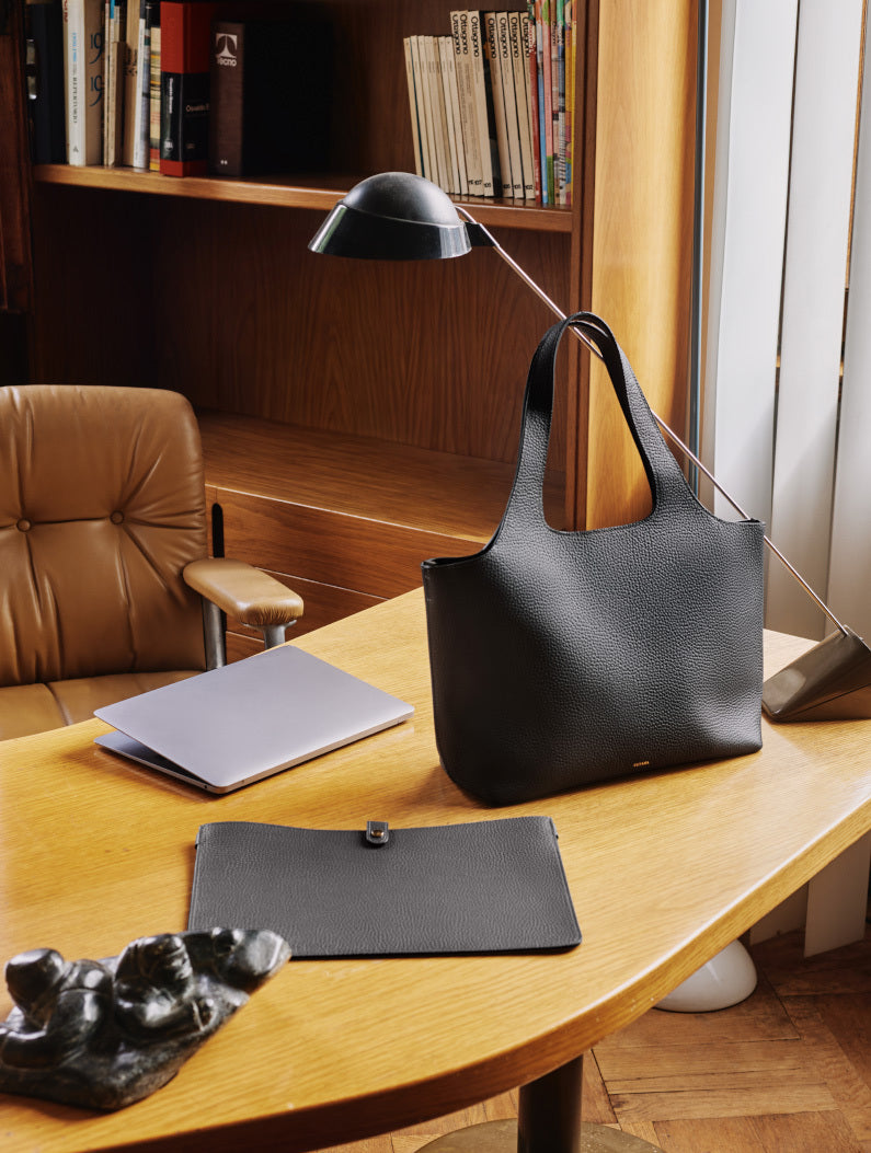 Office desk with a tote bag, laptop, lamp, and folder.