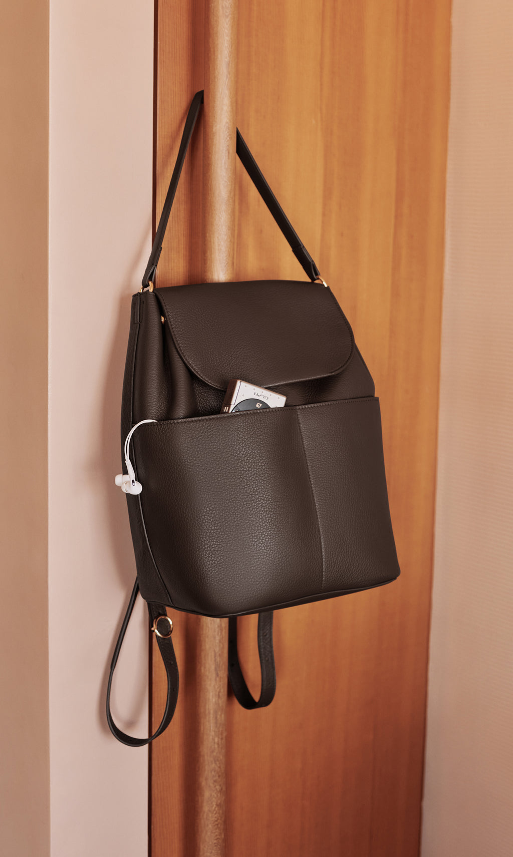 Backpack with a front pocket hanging on a wooden partition.