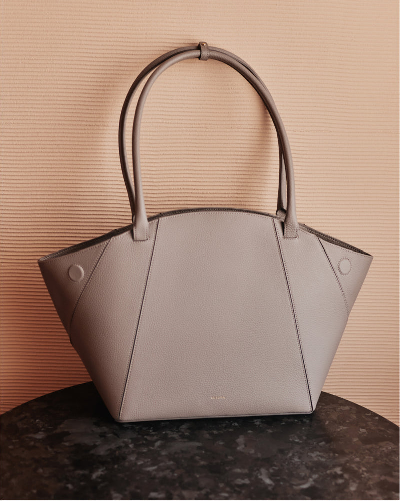 Structured handbag with two handles on a textured surface.