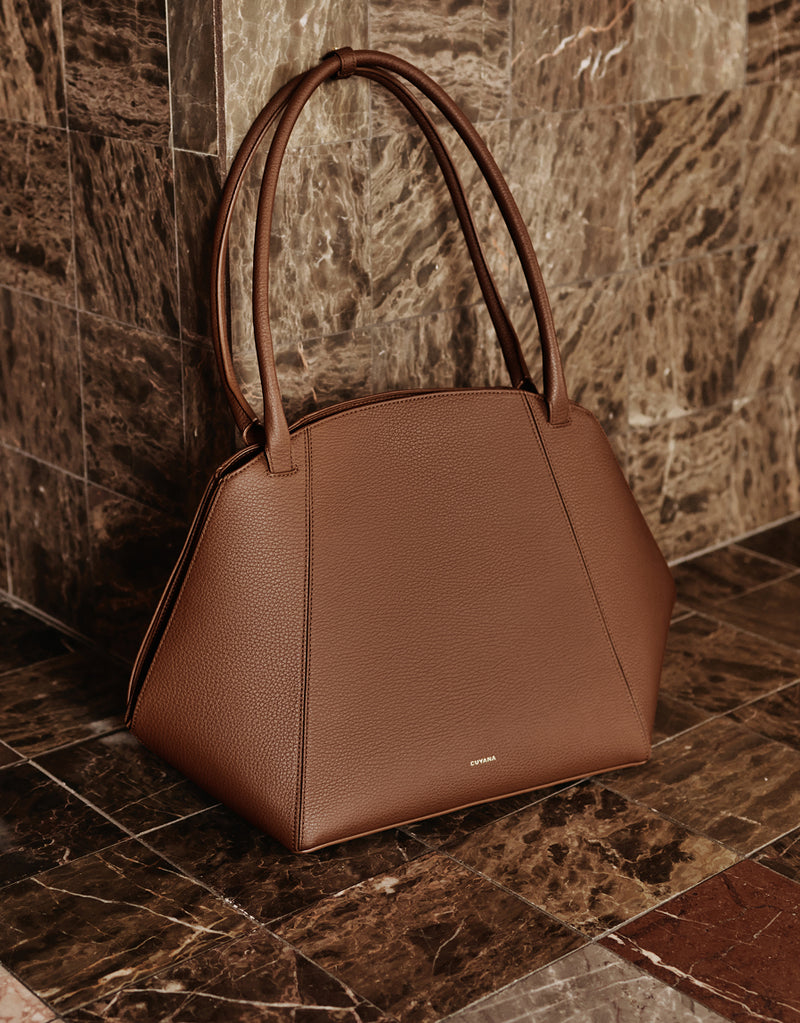 Handbag with curved handles on a stone floor.