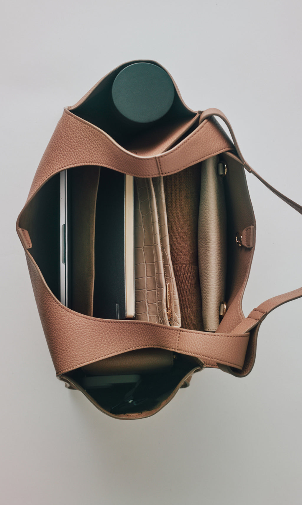 Open handbag with books and croc-embossed leather items inside.