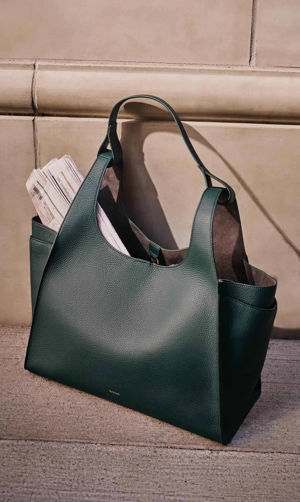 Large tote bag with newspapers inside placed on ground near a wall