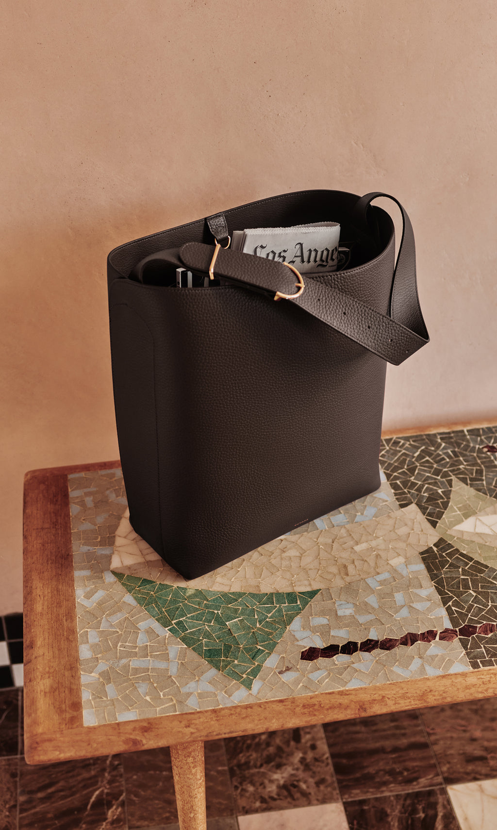 Tote bag on a patterned table with newspapers and items inside.