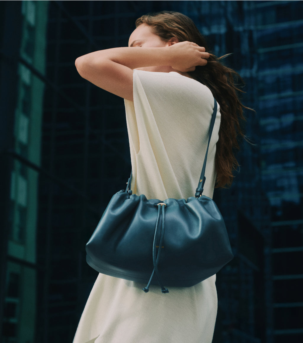 Person with shoulder bag standing near tall building