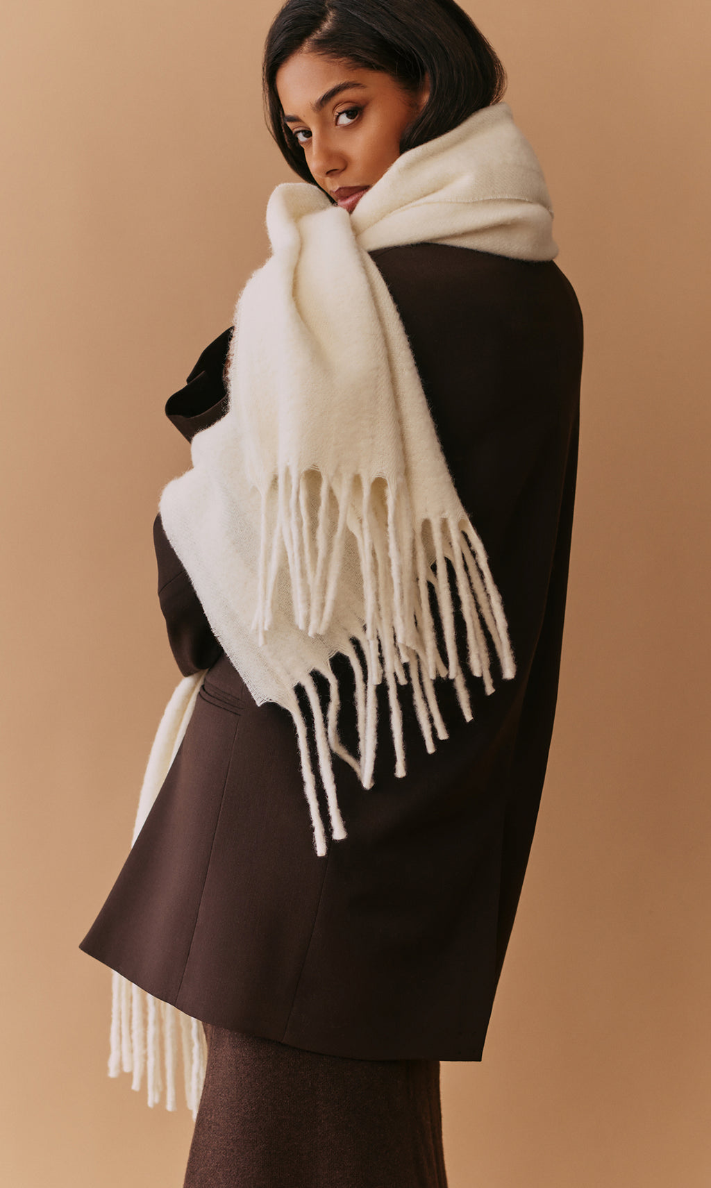 Person wearing coat and large scarf with fringed edges