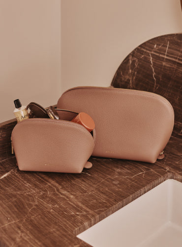 Two toiletry bags on a bathroom counter with grooming items inside.