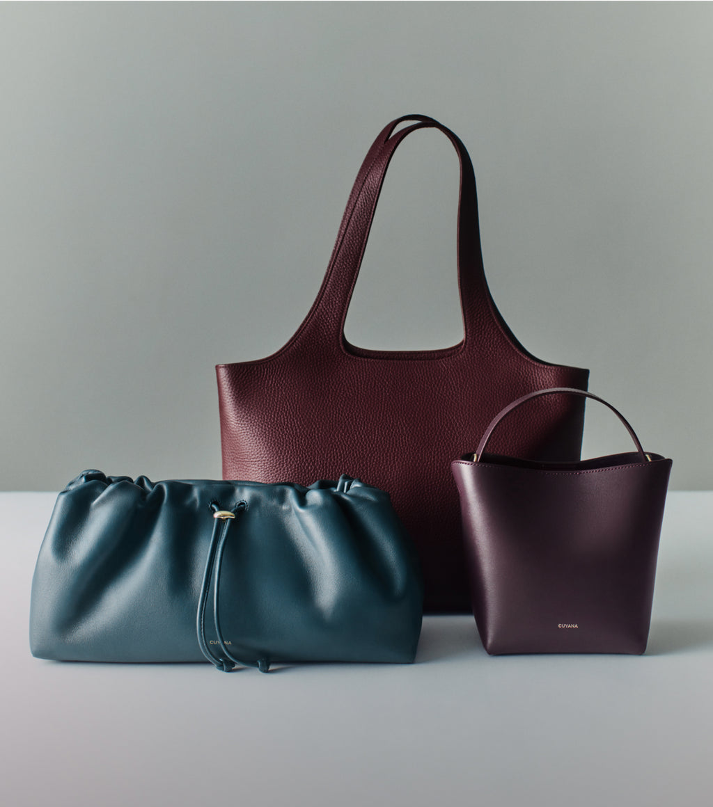 Three handbags displayed on a surface, includes tote, clutch and crossbody styles.