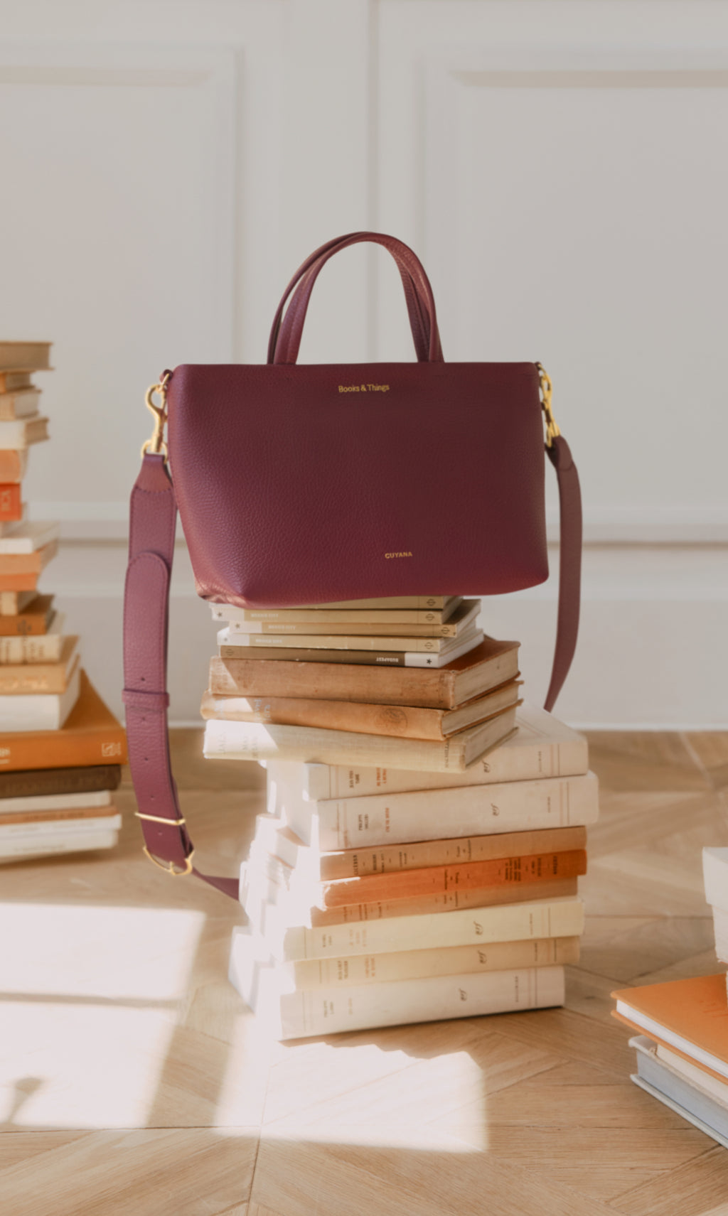Handbag on stacked books in a well-lit room.