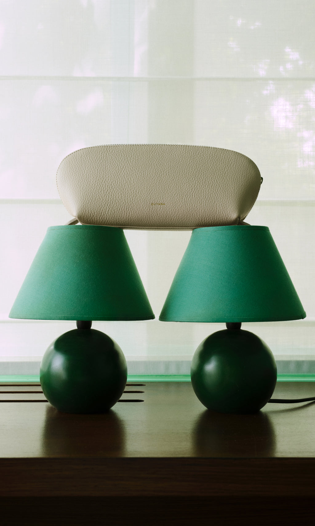 Pouch resting on top of two table lamps with cone-shaped shades.