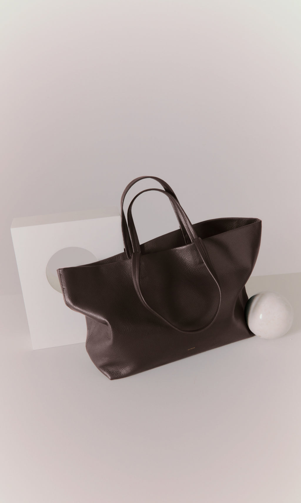 Leather tote bag on display near geometric shapes.