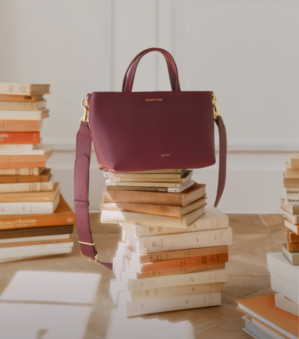 Handbag on stacked books in a room.