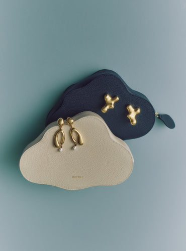 Two cloud-shaped pouches with gold accents on a plain background.