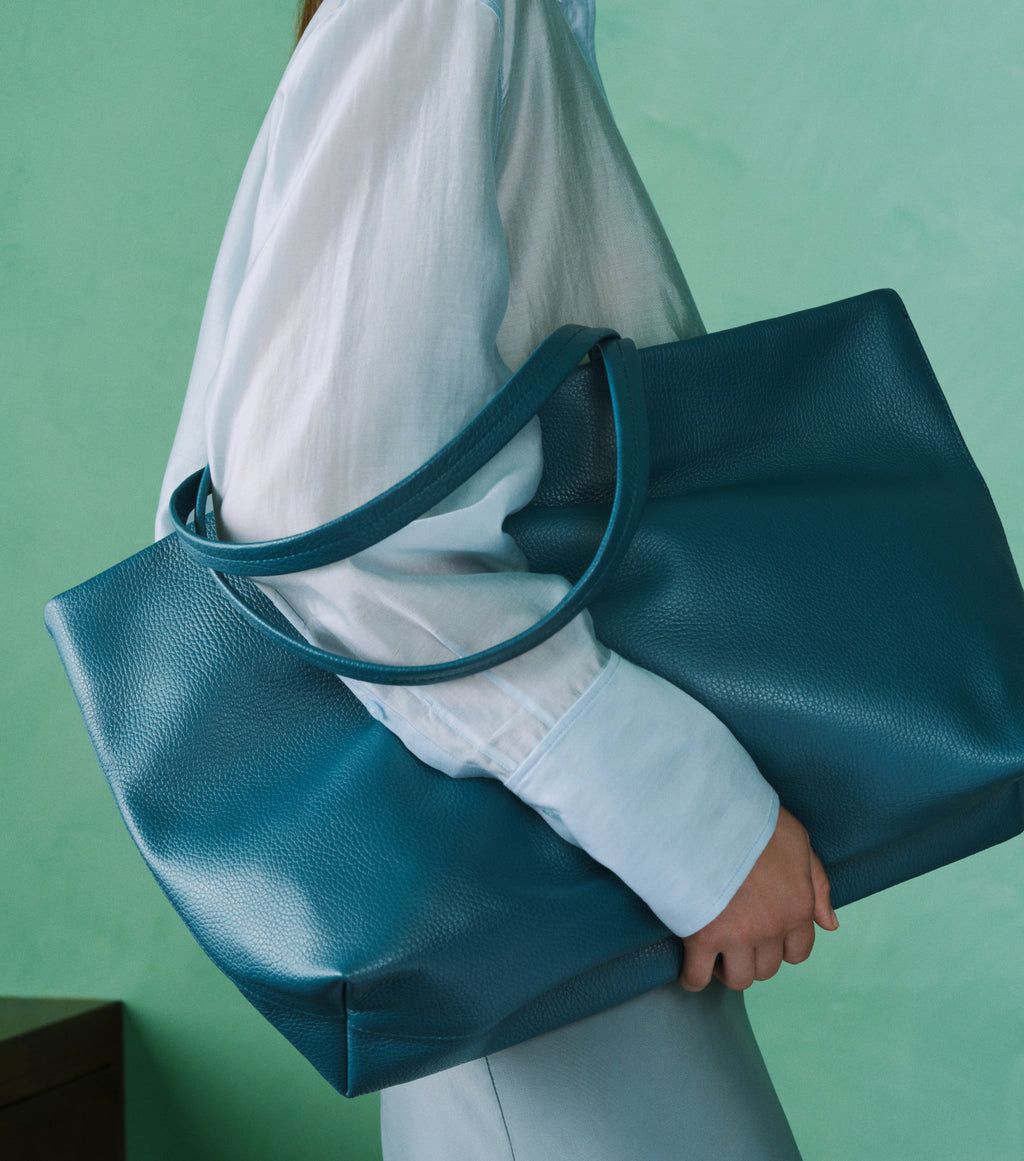 Person holding a large tote bag over shoulder.