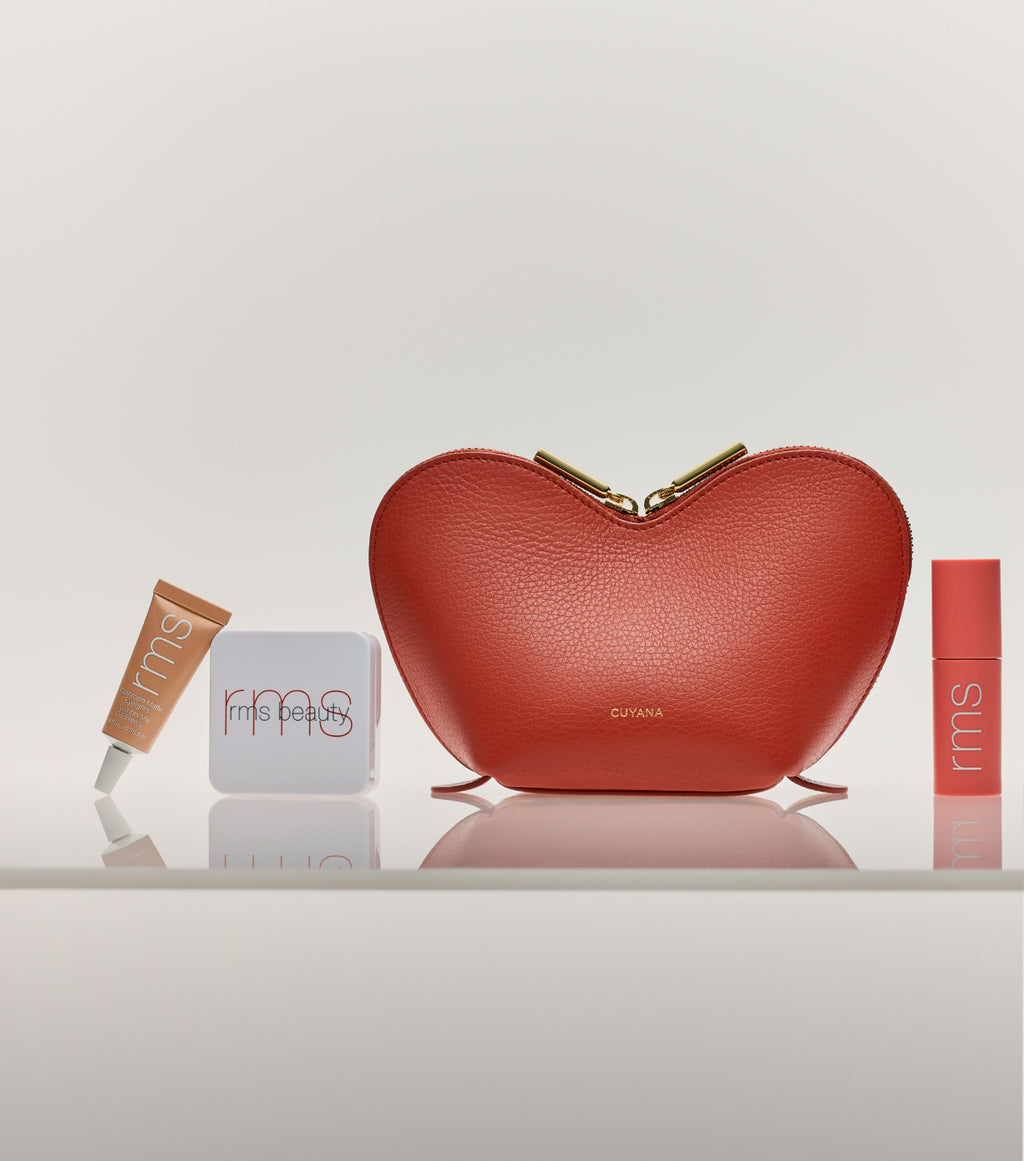 Heart-shaped purse with makeup items on a surface.