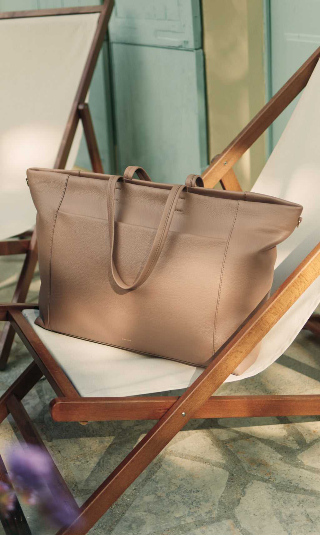 Travel bag on a deck chair near wooden frame in outdoor setting.