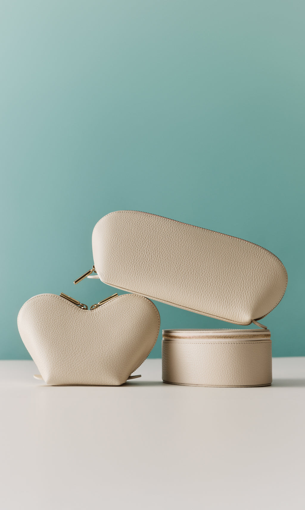 Three leather cosmetic bags stacked on table.