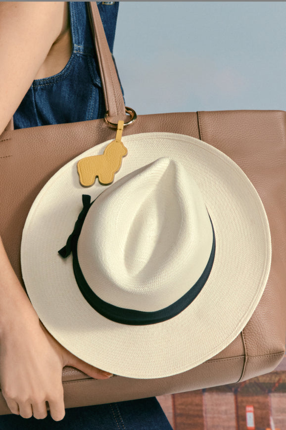 Person holding bag with a hat and a keychain attached.