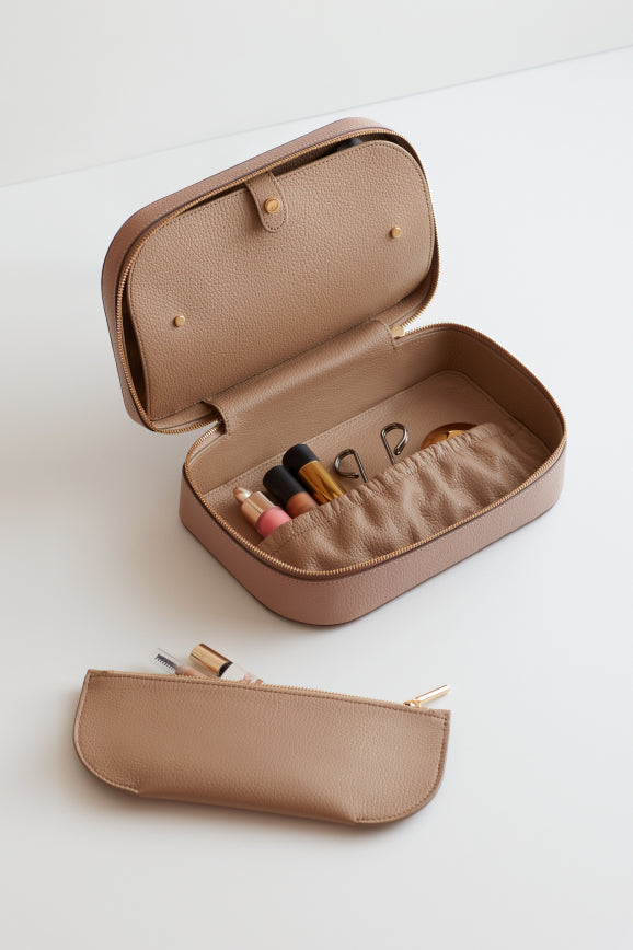 Open cosmetics case with makeup items inside, beside a closed case.