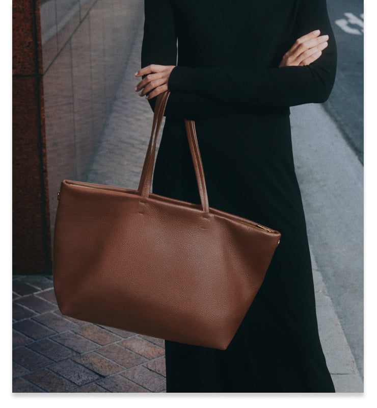 Person holding a large tote bag on the street.