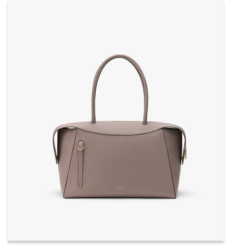 Handbag with two handles and zipper top on plain background.