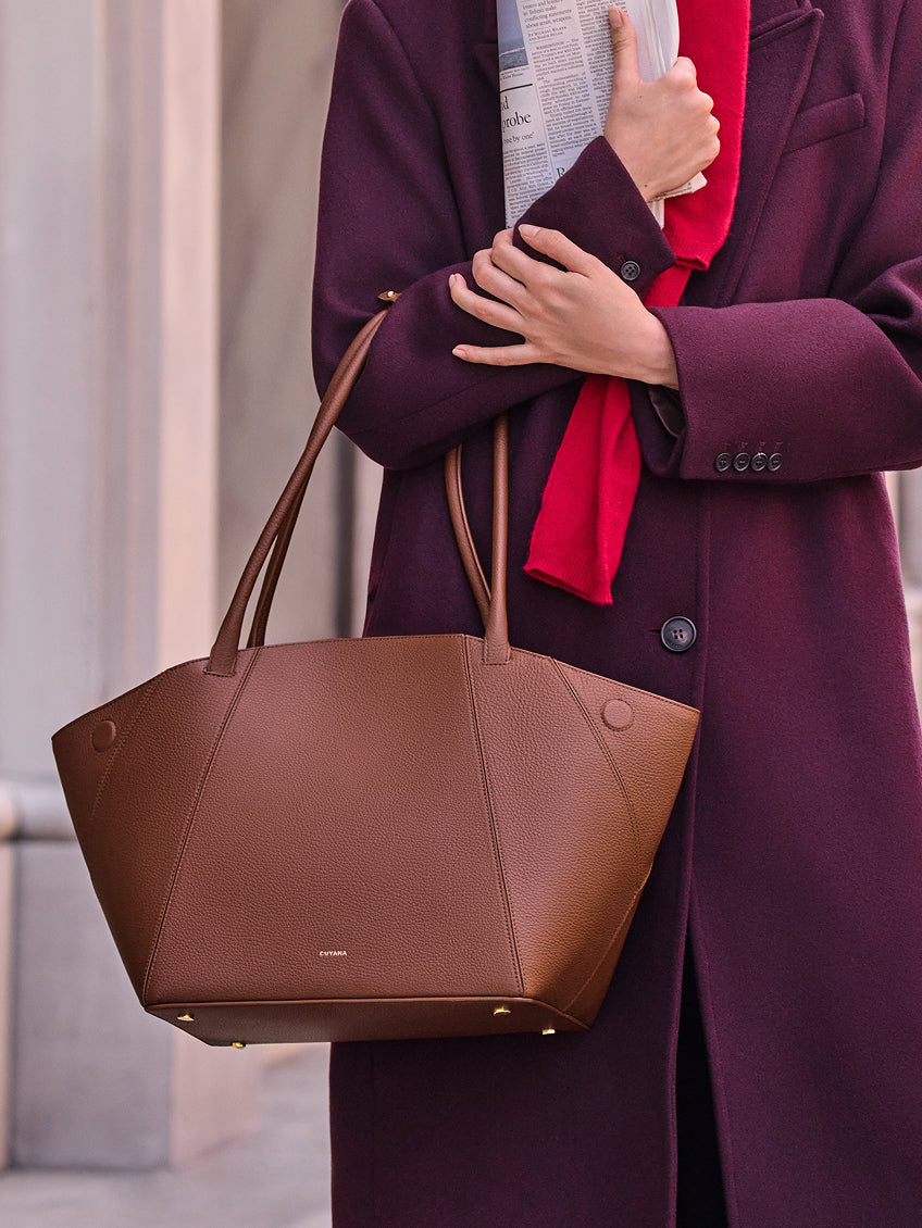 Person holding a newspaper and a handbag with long handles