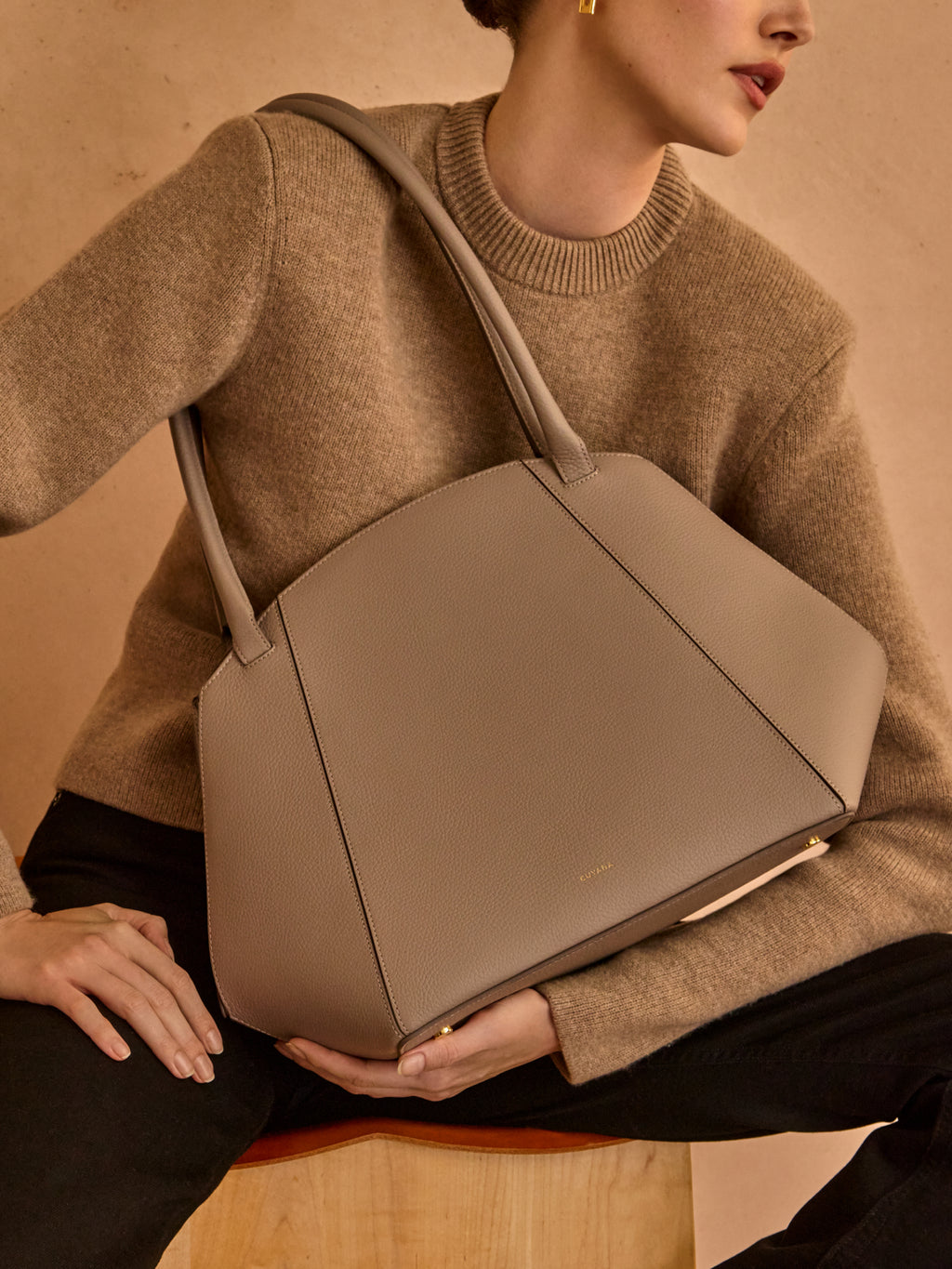 Person holding a large tote bag while sitting.