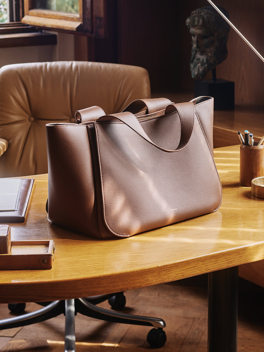 A tote bag on a wooden desk in an office setting.