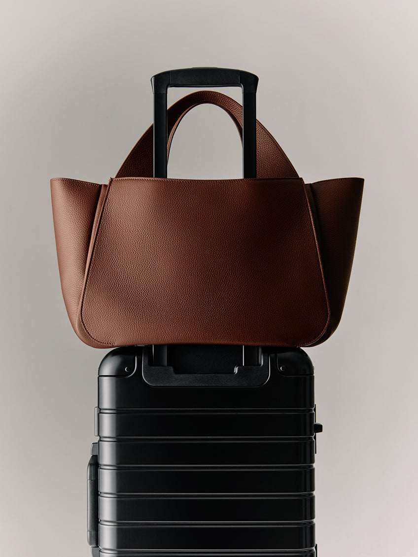 Travel bag on top of a suitcase with extended handle.