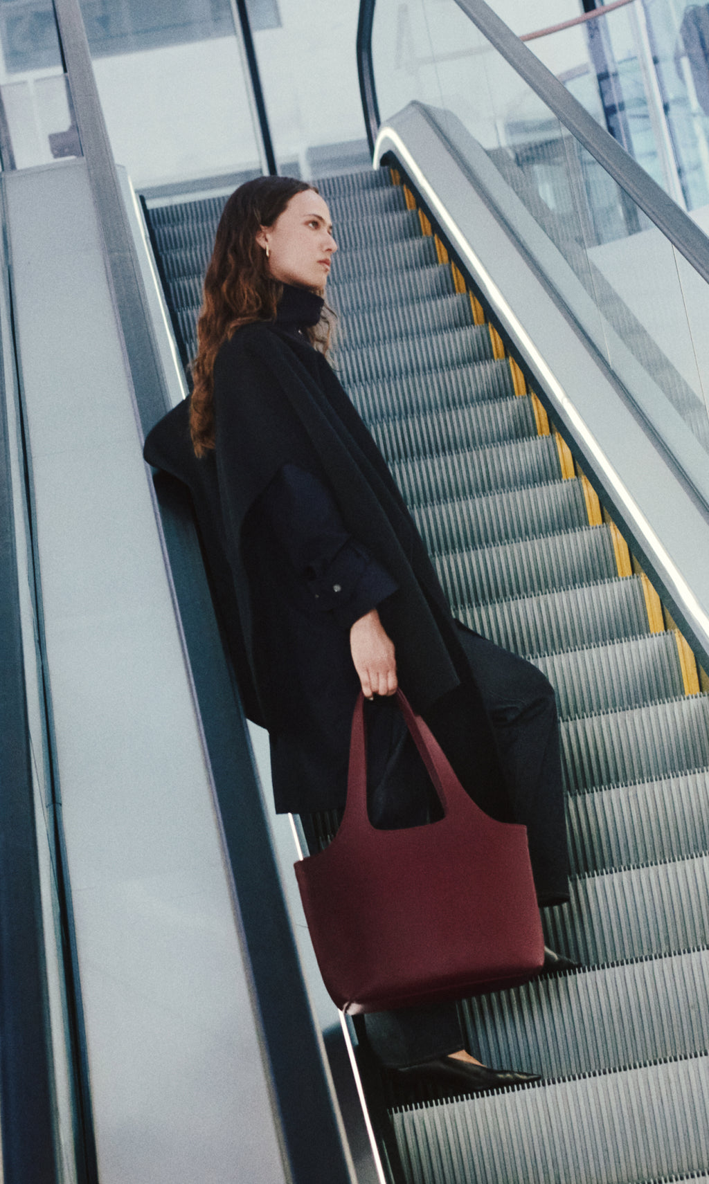 Person on escalator carrying large tote bag