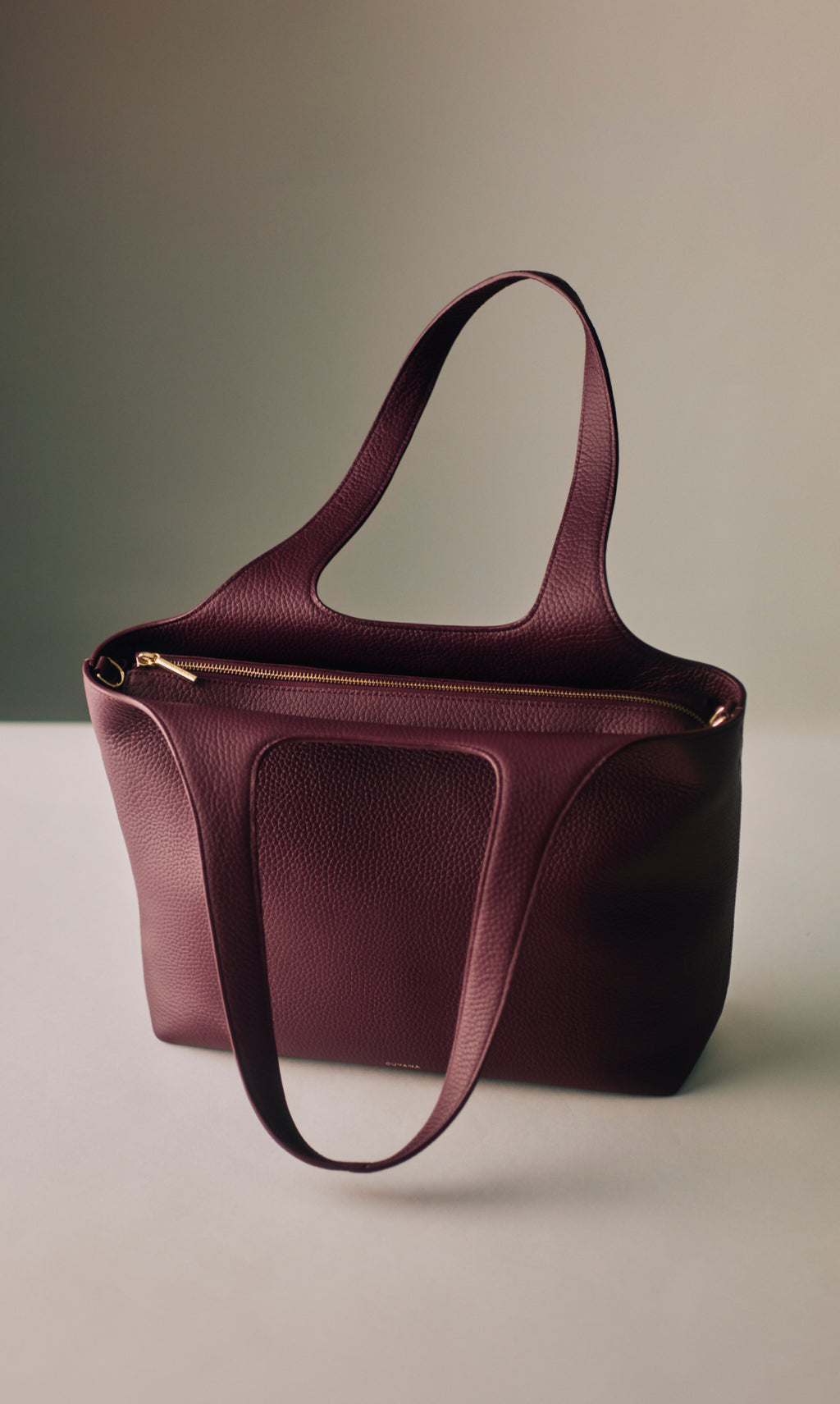 Tote bag with long handles and zippered top on a flat surface.