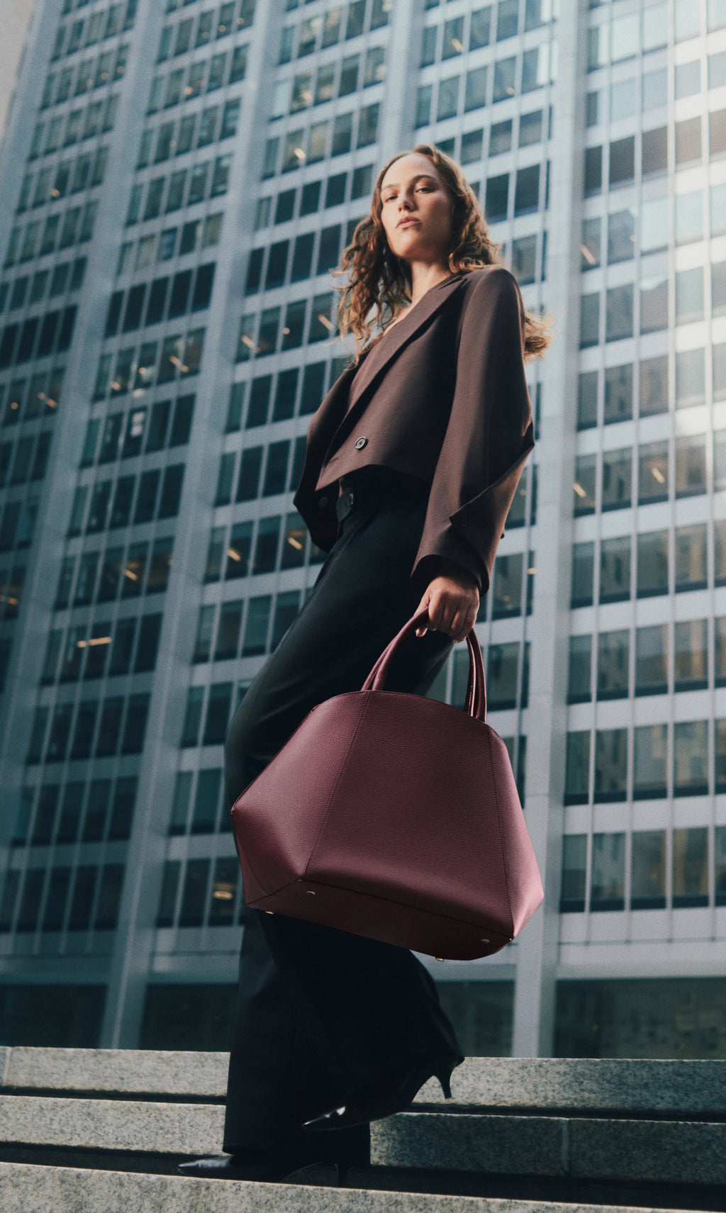 Person walking with a large handbag in front of tall building