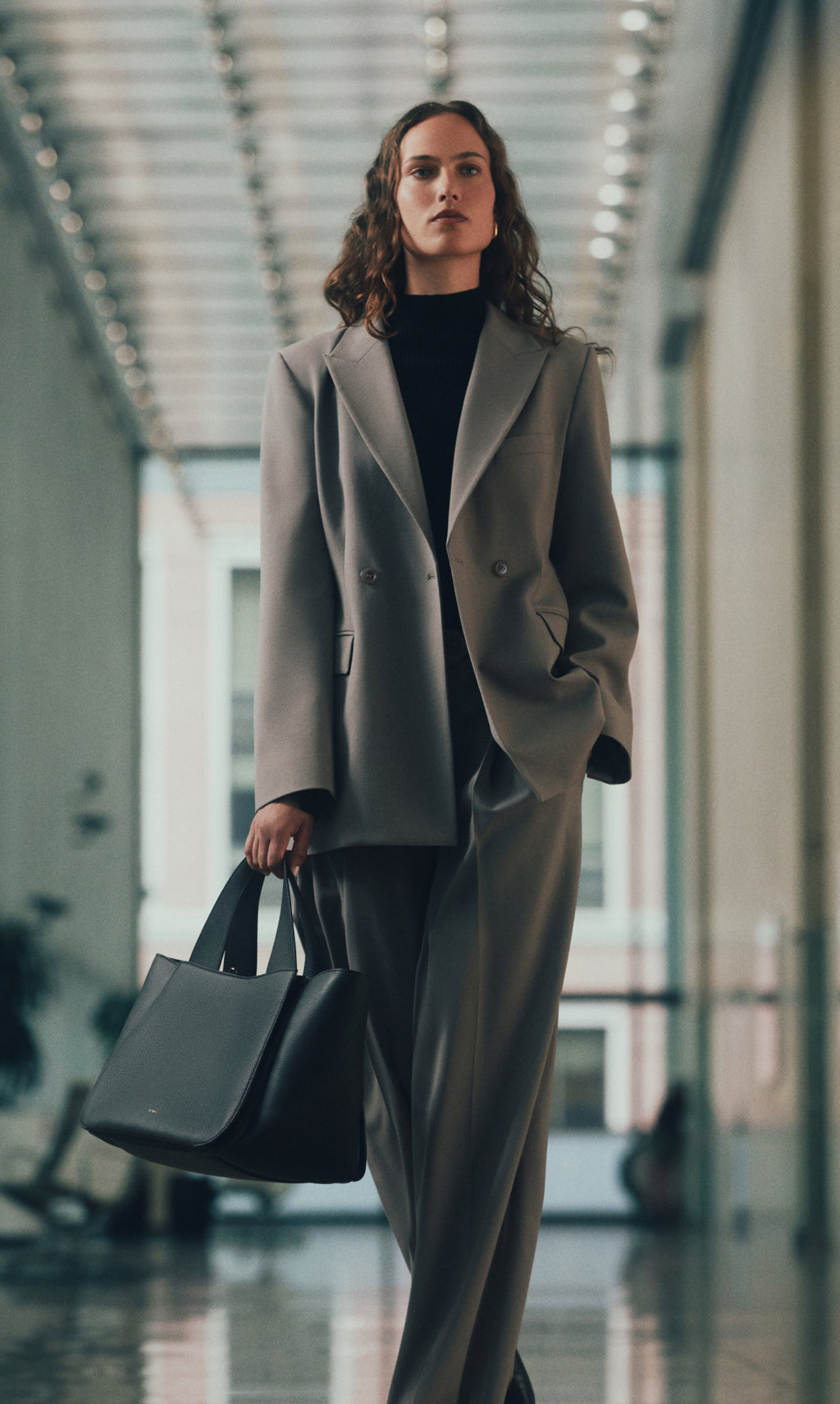 Person in a suit walking in a hallway holding a large bag