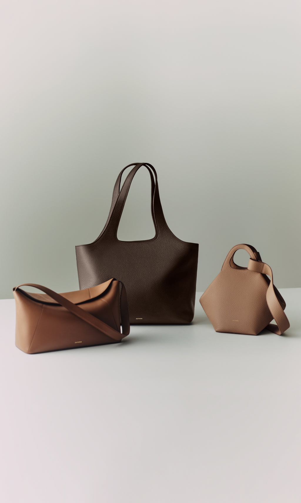 Three elegant handbags displayed on a light surface